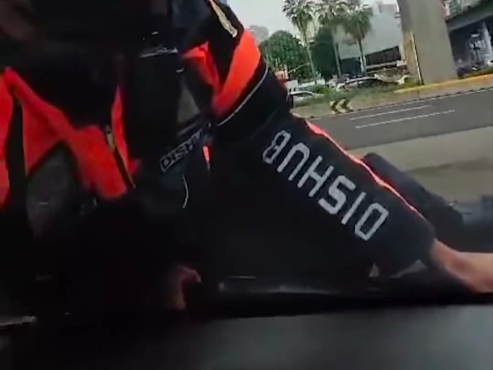 Petugas Dishub tersangkut di kap mobil.