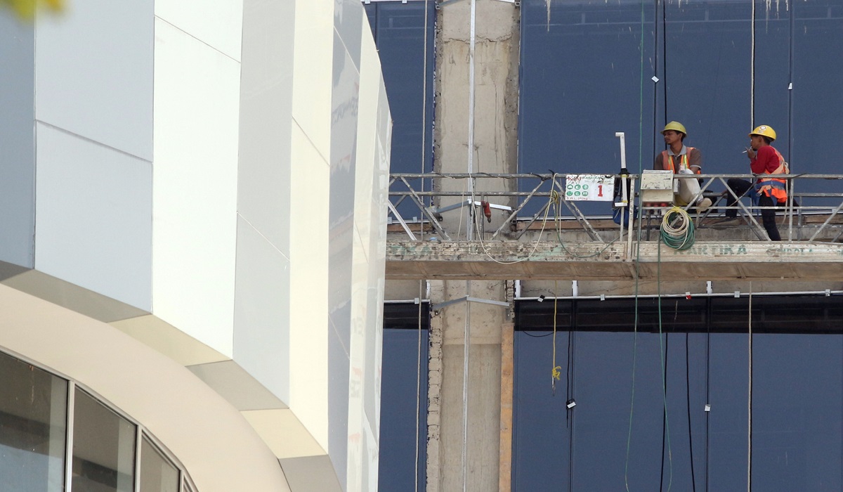Pekerja meyelesaikan pembangunan gedung bertingkat menggunakan gondola di Bogor, Jawa Barat.