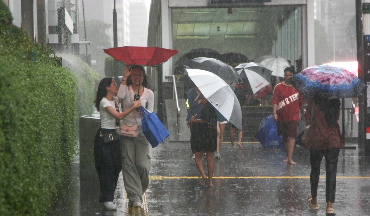 Pejalan kaki menerobos hujan deras menggunakan jasa ojek payung di Jalan Thamrin, Jakarta, 11 Januari 2024.