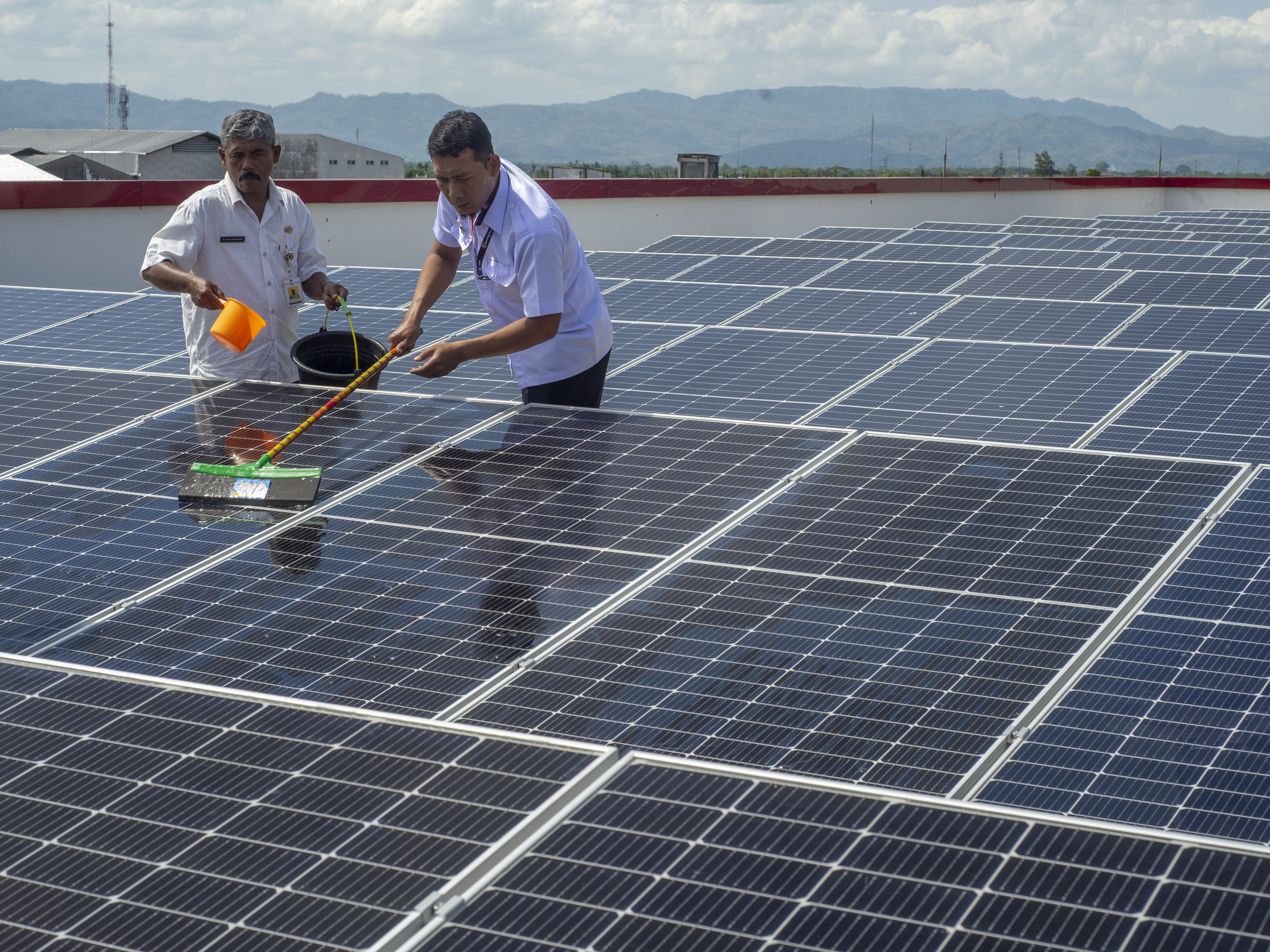 Petugas membersihkan permukaan panel surya yang terpasang di Pasar Gedhe, Klaten, Jawa Tengah, Rabu (6/12/2023).