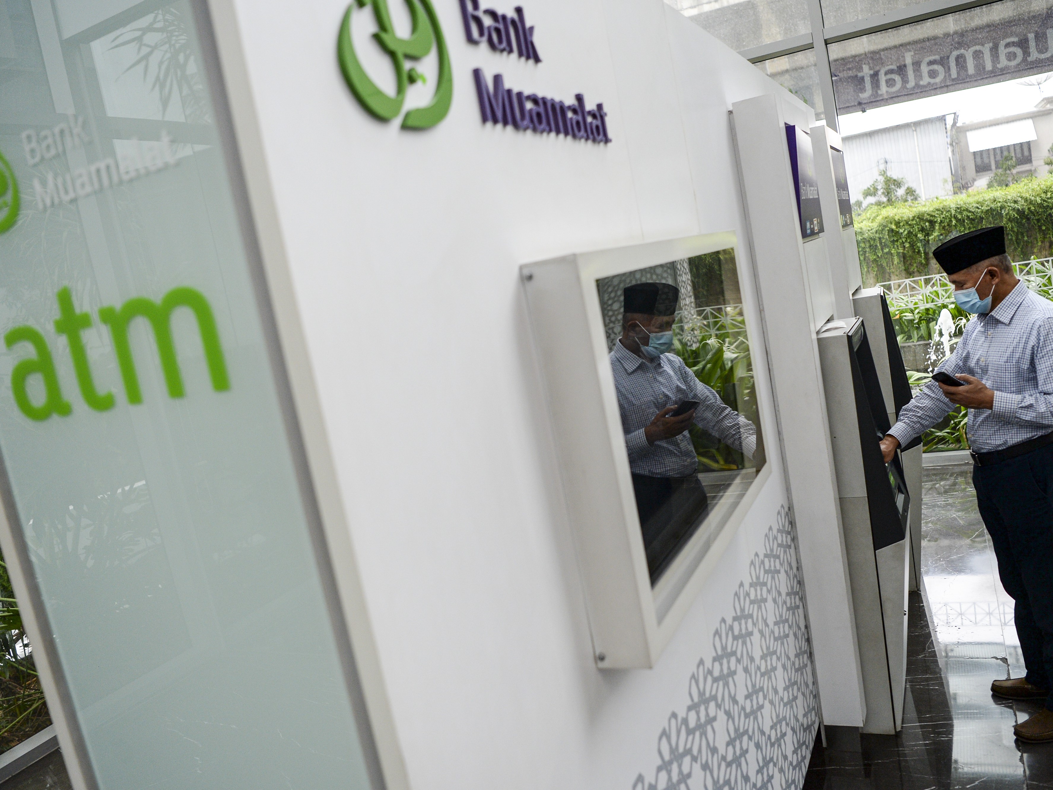 Seorang nasabah melakukan transaksi melalui mesin Anjungan Tunai Mandiri (ATM) Bank Muamalat di Kantor Bank Muamalat, Jakarta.