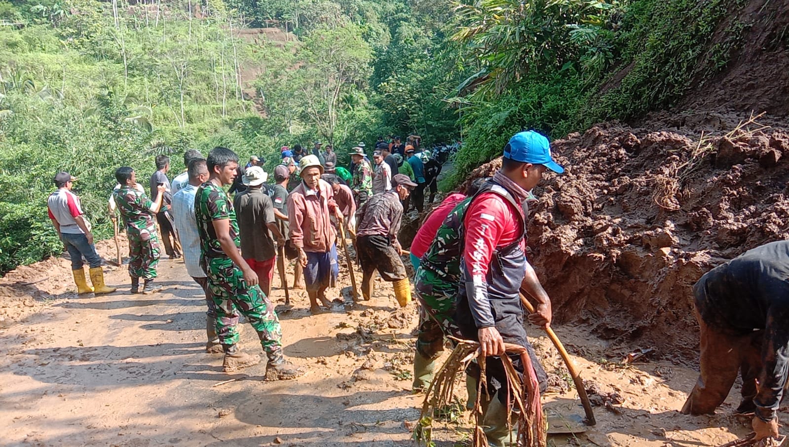 Aparat dan warga bergotong royong membersihkan material tanah longsor di jalan penghubung desa di Kabupaten Tasikmalaya