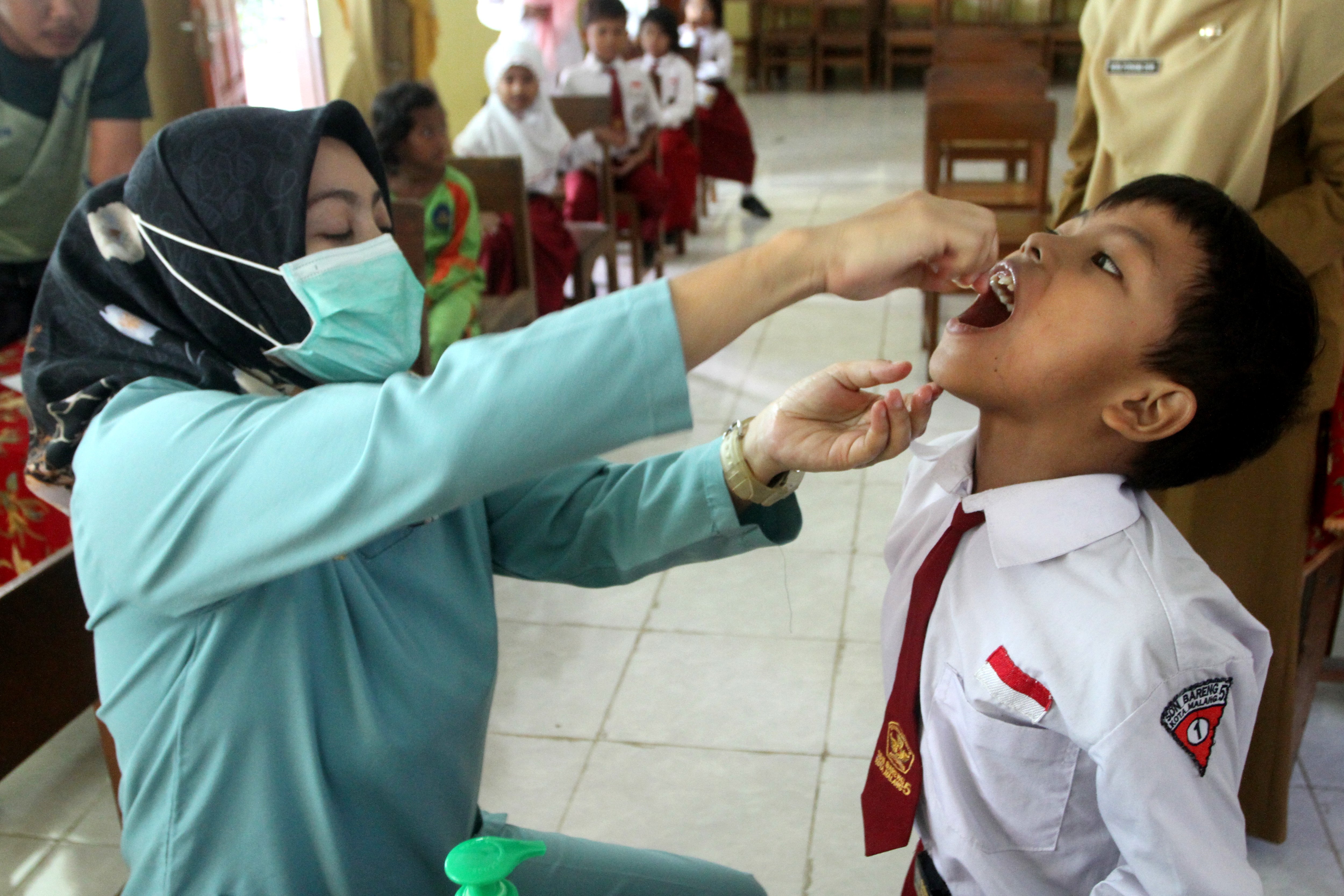  VAKSINASI: Petugas kesehatan meneteskan vaksin polio kepada seorang siswa saat pelaksanaan Sub PIN Polio di SDN Bareng 5, Malang