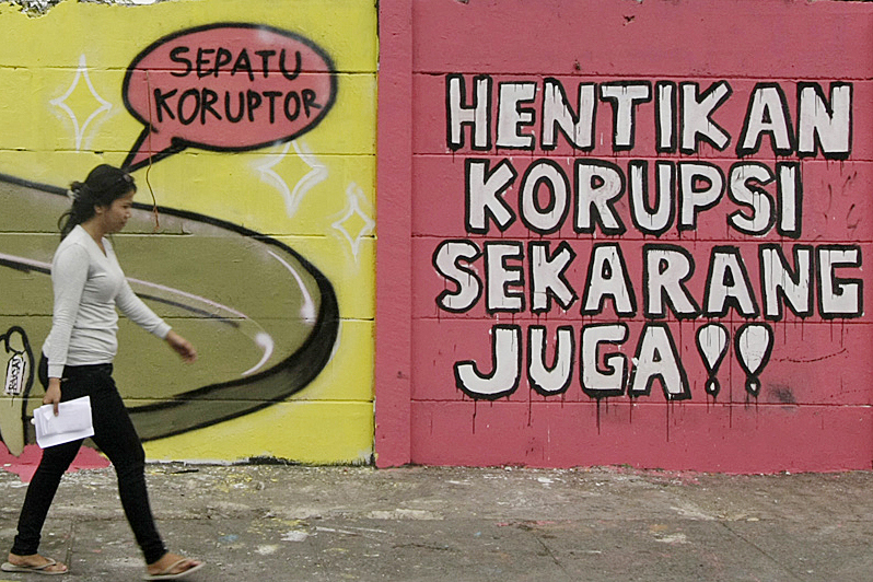 Warga melintas di dekat gambar mural anti korupsi yang bertuliskan 