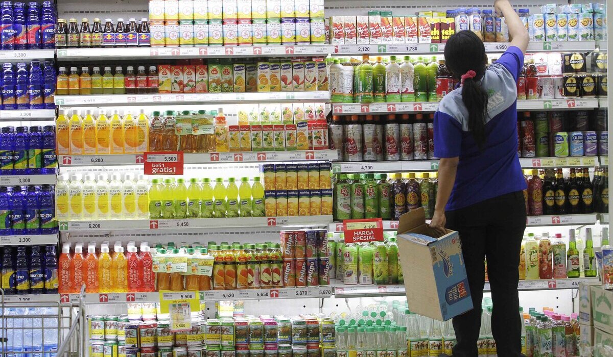 Pengunjung melintas di depan lemari minuman di Carrefour Lebak Bulus, Jakarta Selatan.