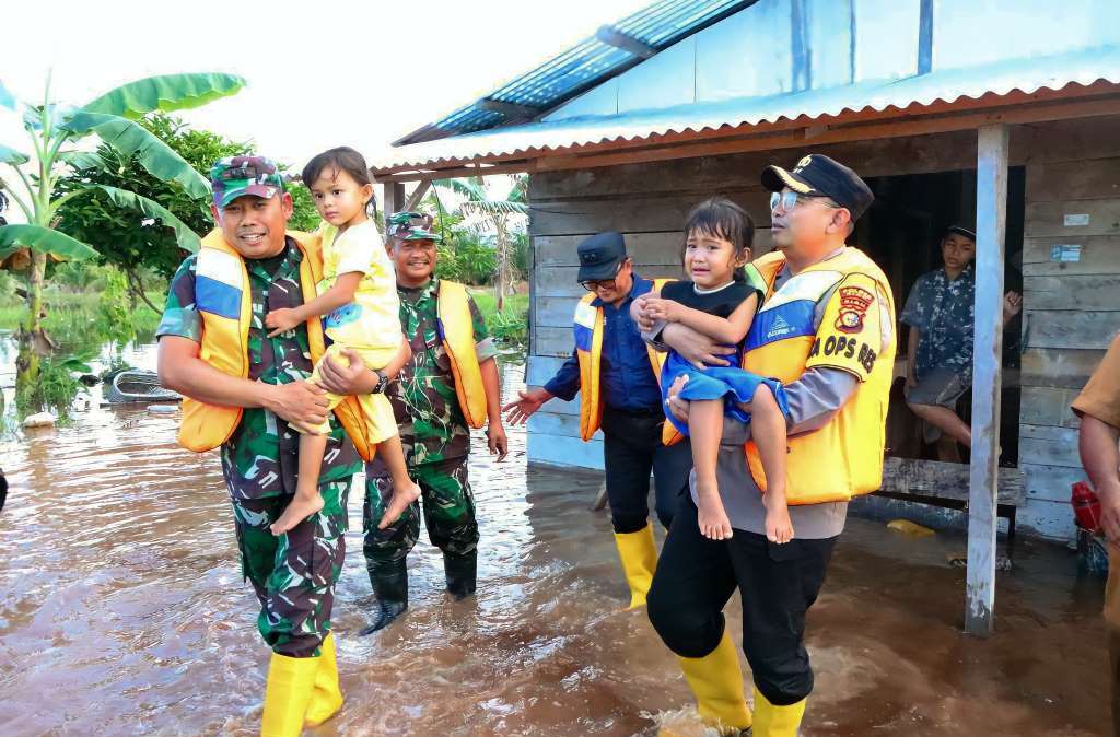 Kapolres Siak (kanan) didampingi Dandim 0322 Siak (kiri) membantu mengevakuasi anak-anak korban banjir di Kecamatan Sei Mandau, Siak, Riau.