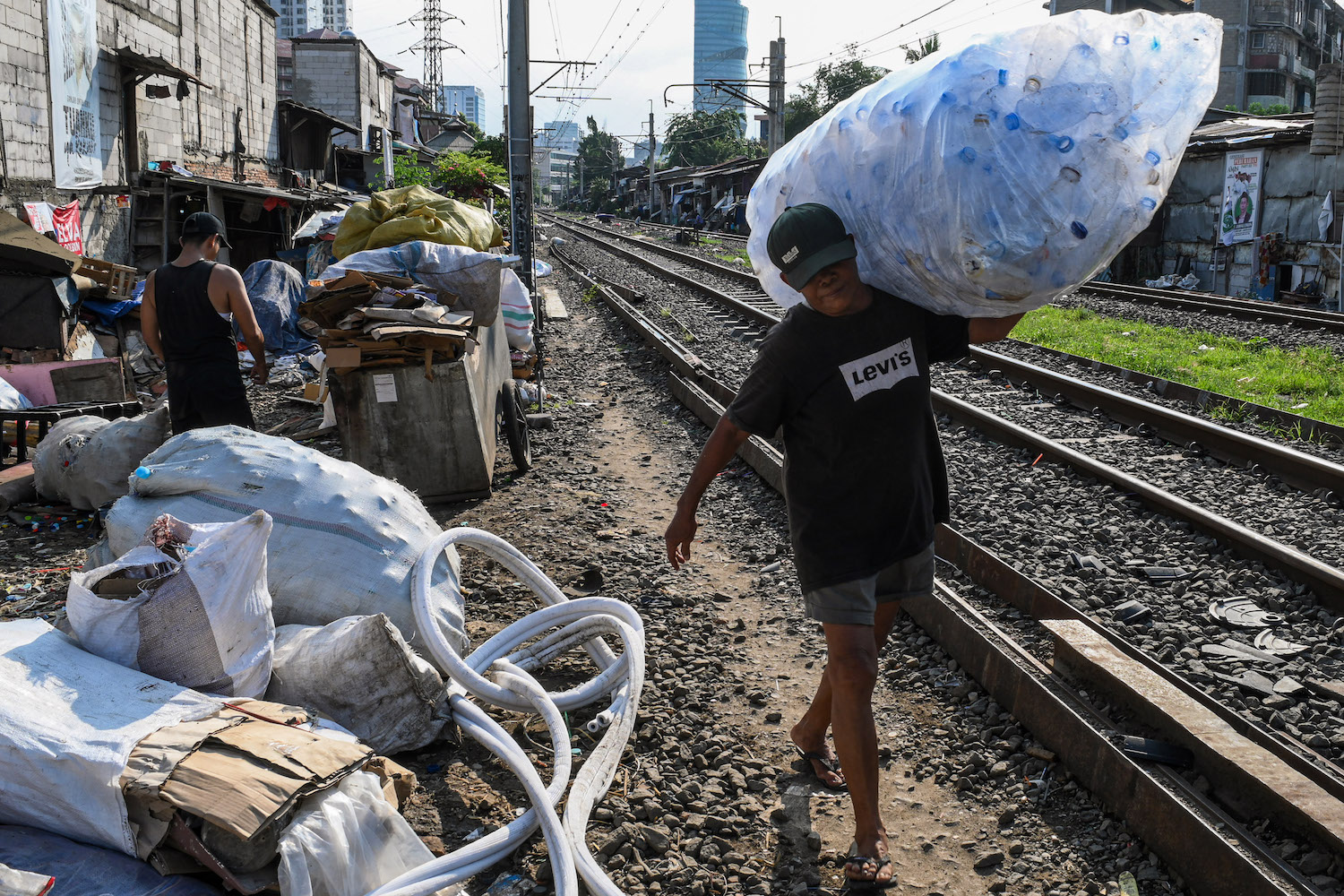 Pemulung memikul botol plastik di area perlintasan kereta api Palmerah-Tanah Abang, Jakarta, kemarin.