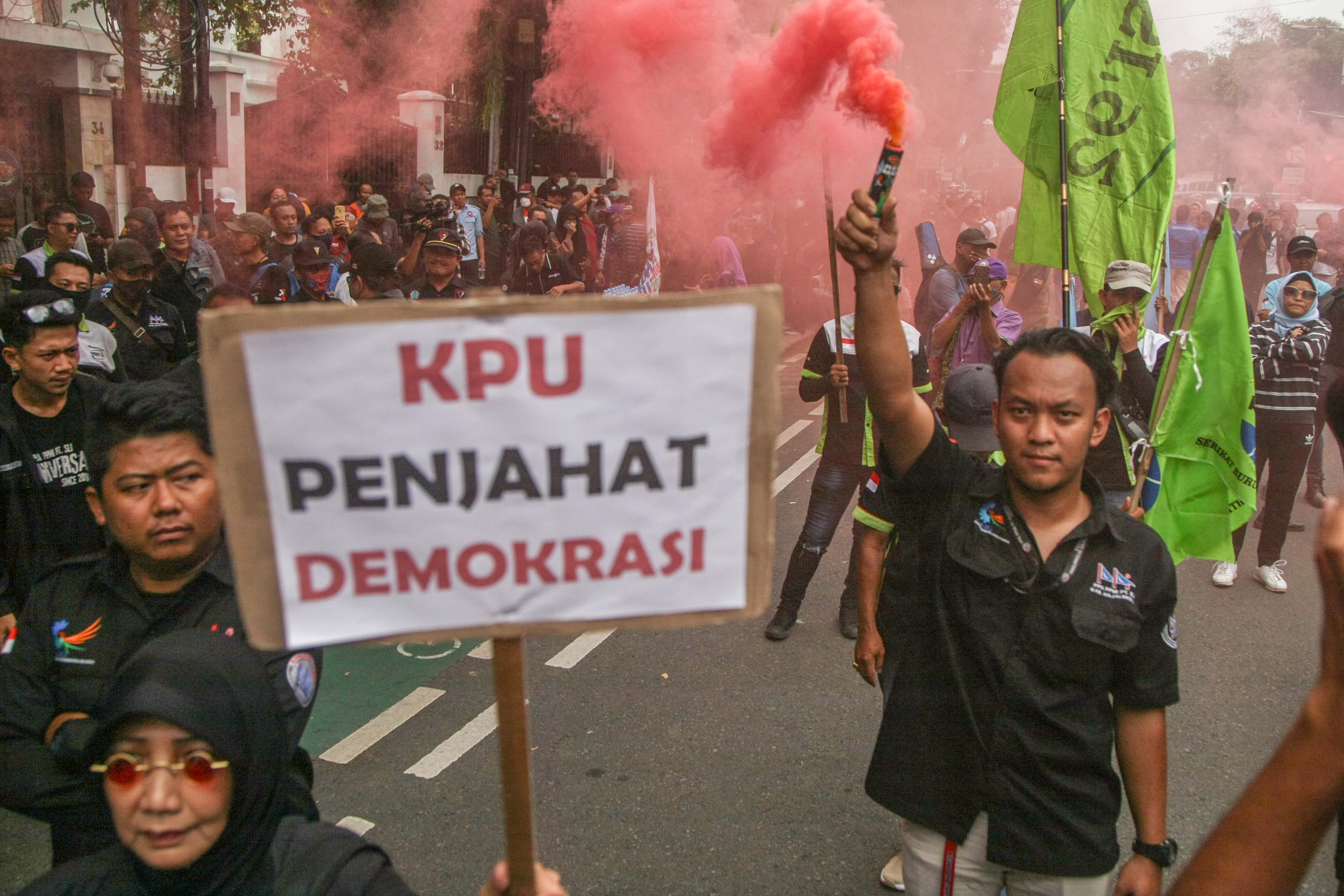 Massa Poros Buruh menyalakan flare saat berunjuk rasa di depan Gedung KPU, Jakarta