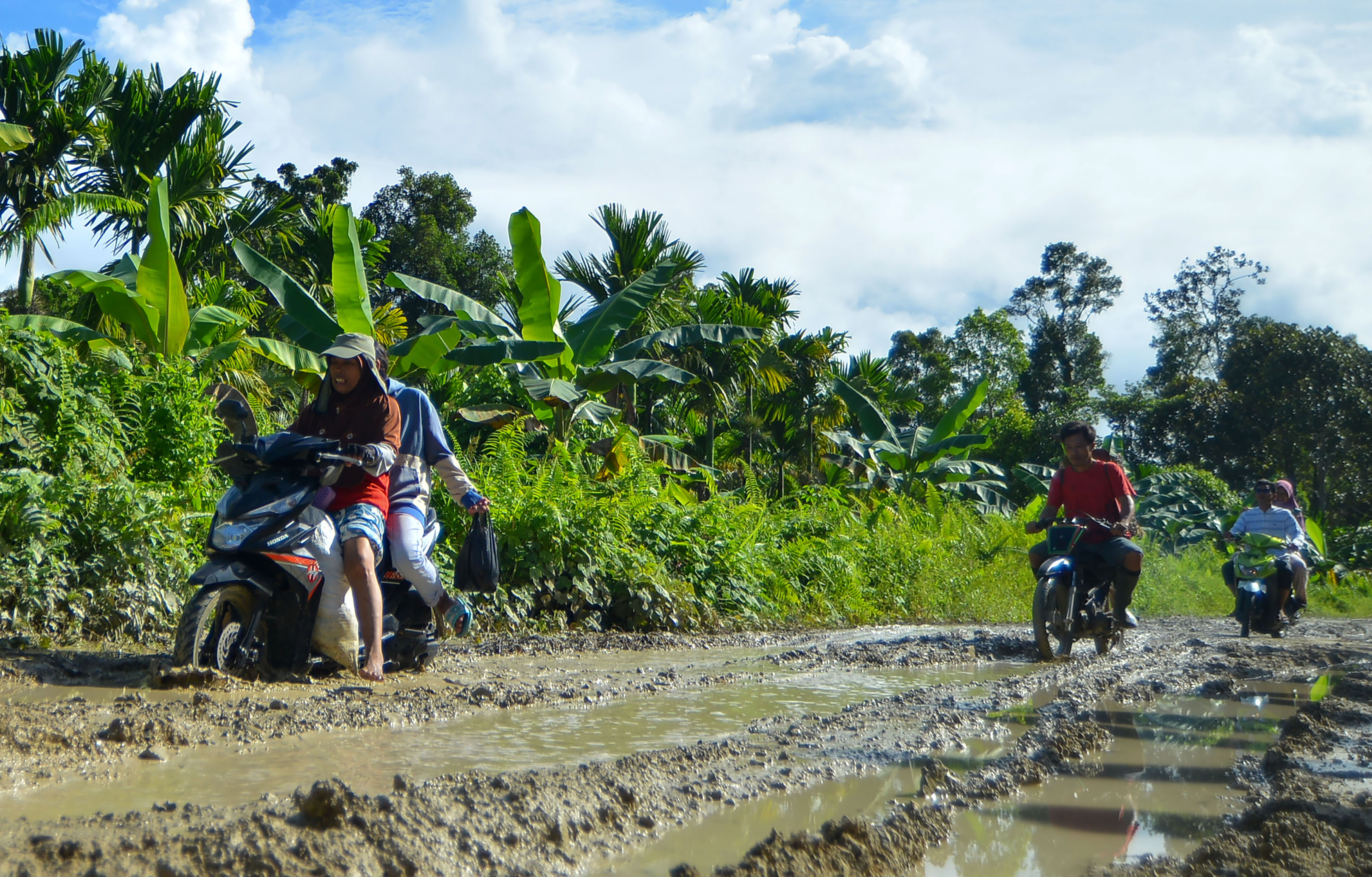 Pengendara melewati jalur berlumpur di Jalan Trans Mentawai, di Desa Madobag, Siberut Selatan, Kabupaten Kepulauan Mentawai,