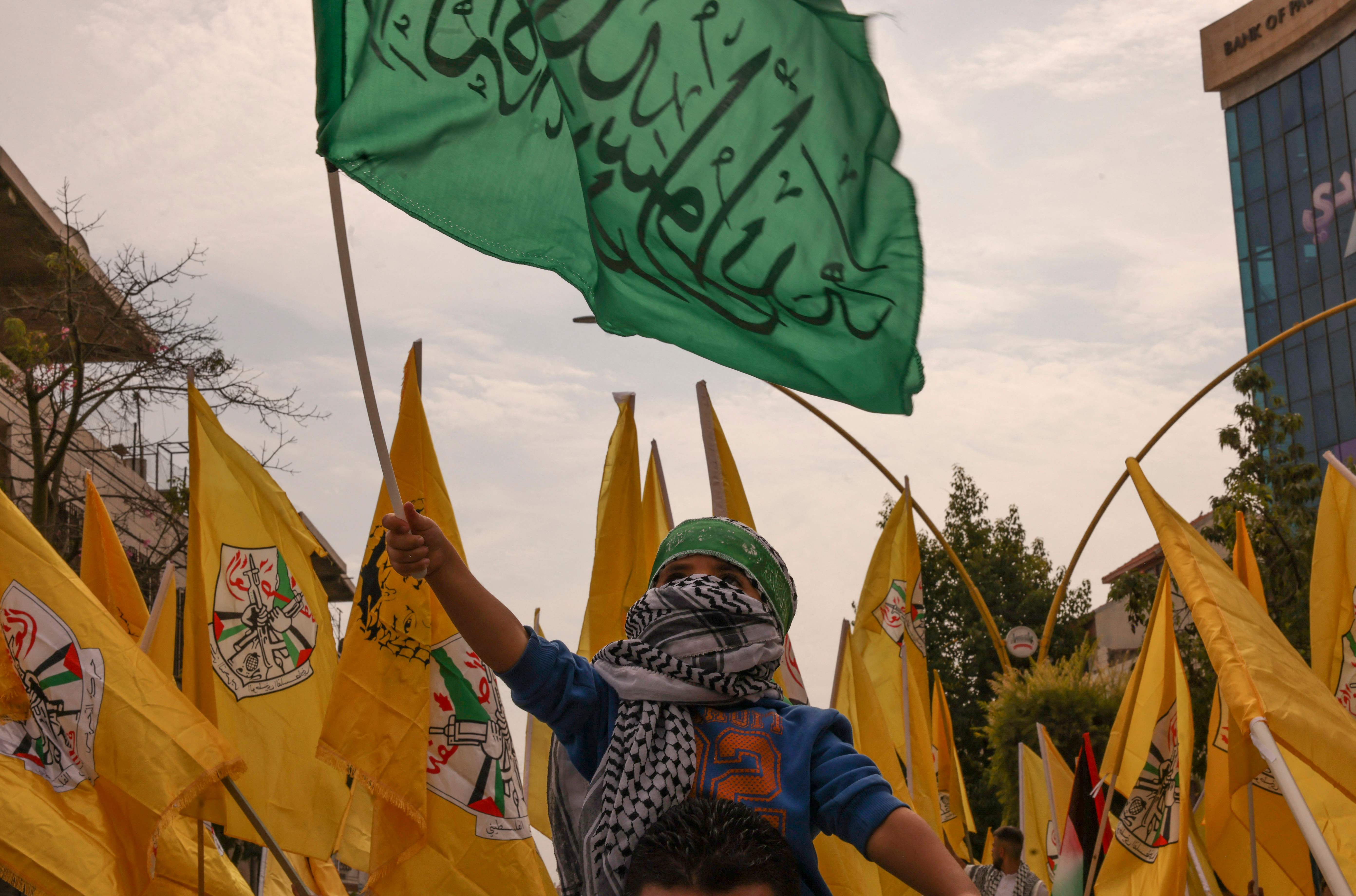 Seorang anak mengibarkan bendera Hamas dengan latar bendera Fatah, saat pawai solidaritas di Jalur Gaza, pada 27 Oktober 2023.