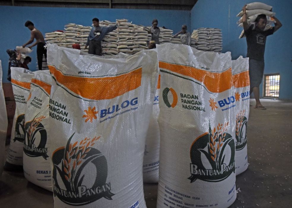 Para pekerja mengangkut beras di gudang Perum Bulog.