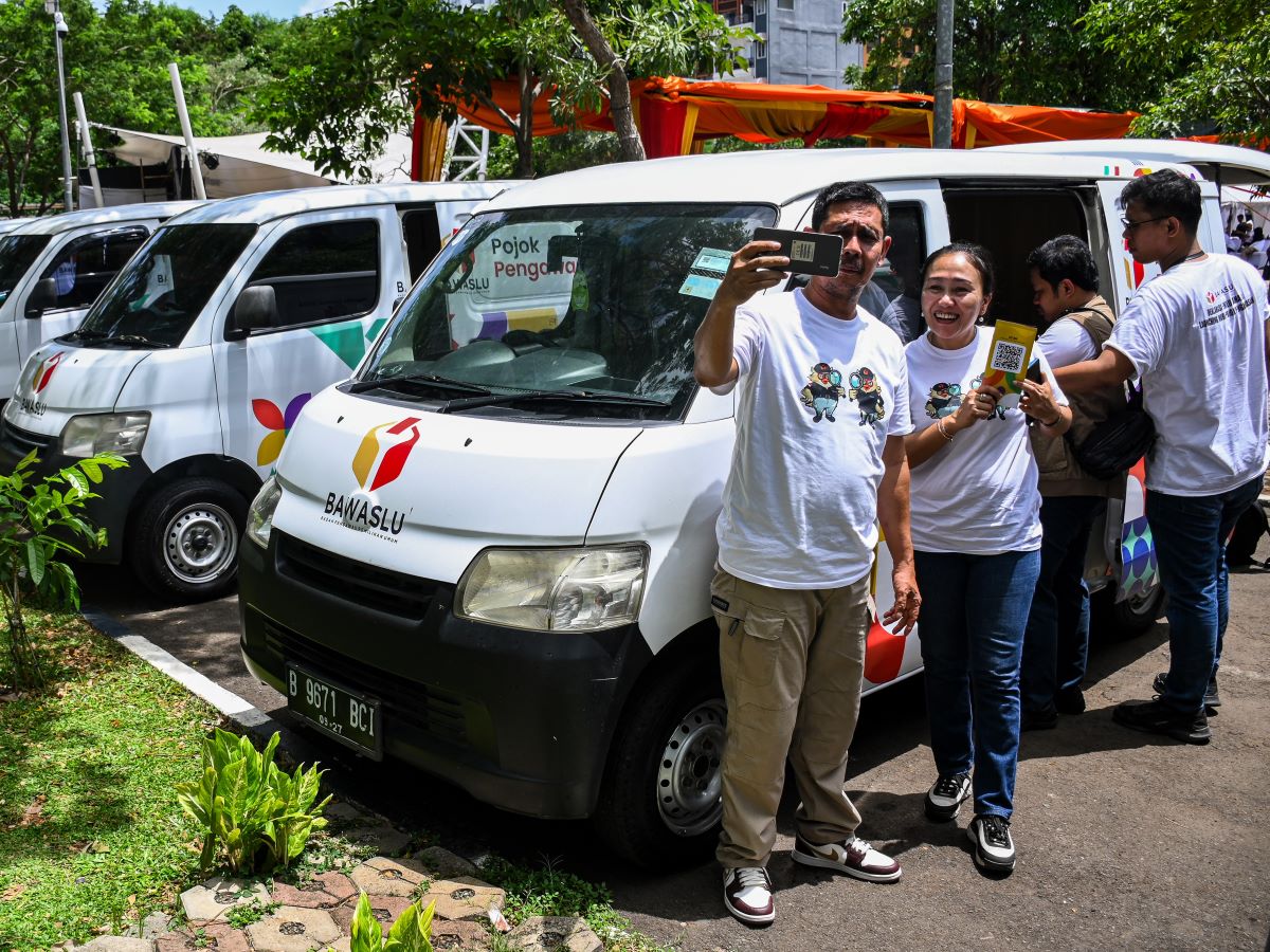 Warga berswafoto di dekat mobil Pojok Pengawasan Bawaslu di Thamrin 10, Jakarta, Minggu (21/1/2024).