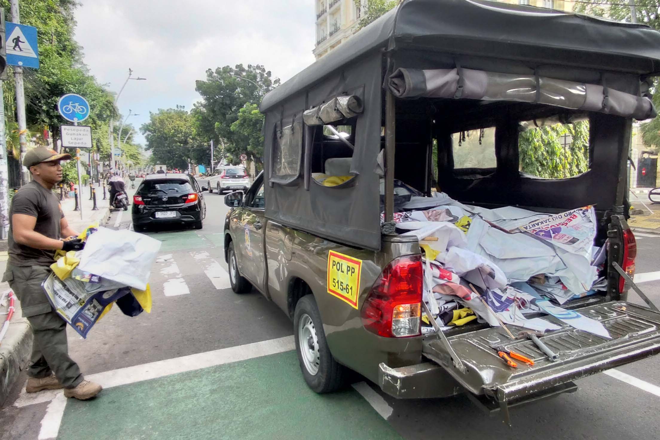 Petugas Satpol PP menurunkan alat peraga kampanye (APK) di masa tenang Pemilu 2024.