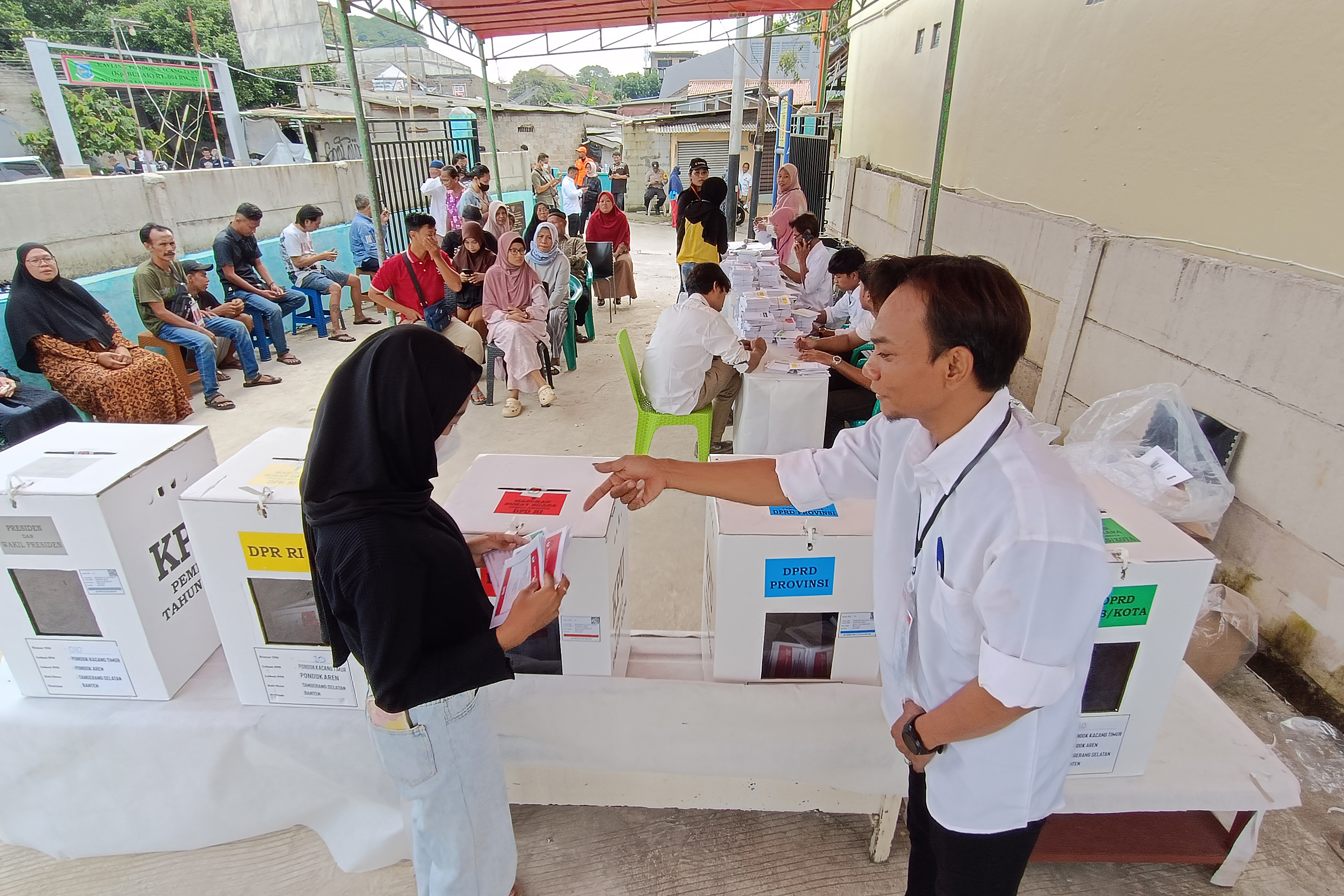 Warga dibantu anggota Kelompok Penyelenggara Pemungutan Suara (KPPS) memberikan hak suaranya