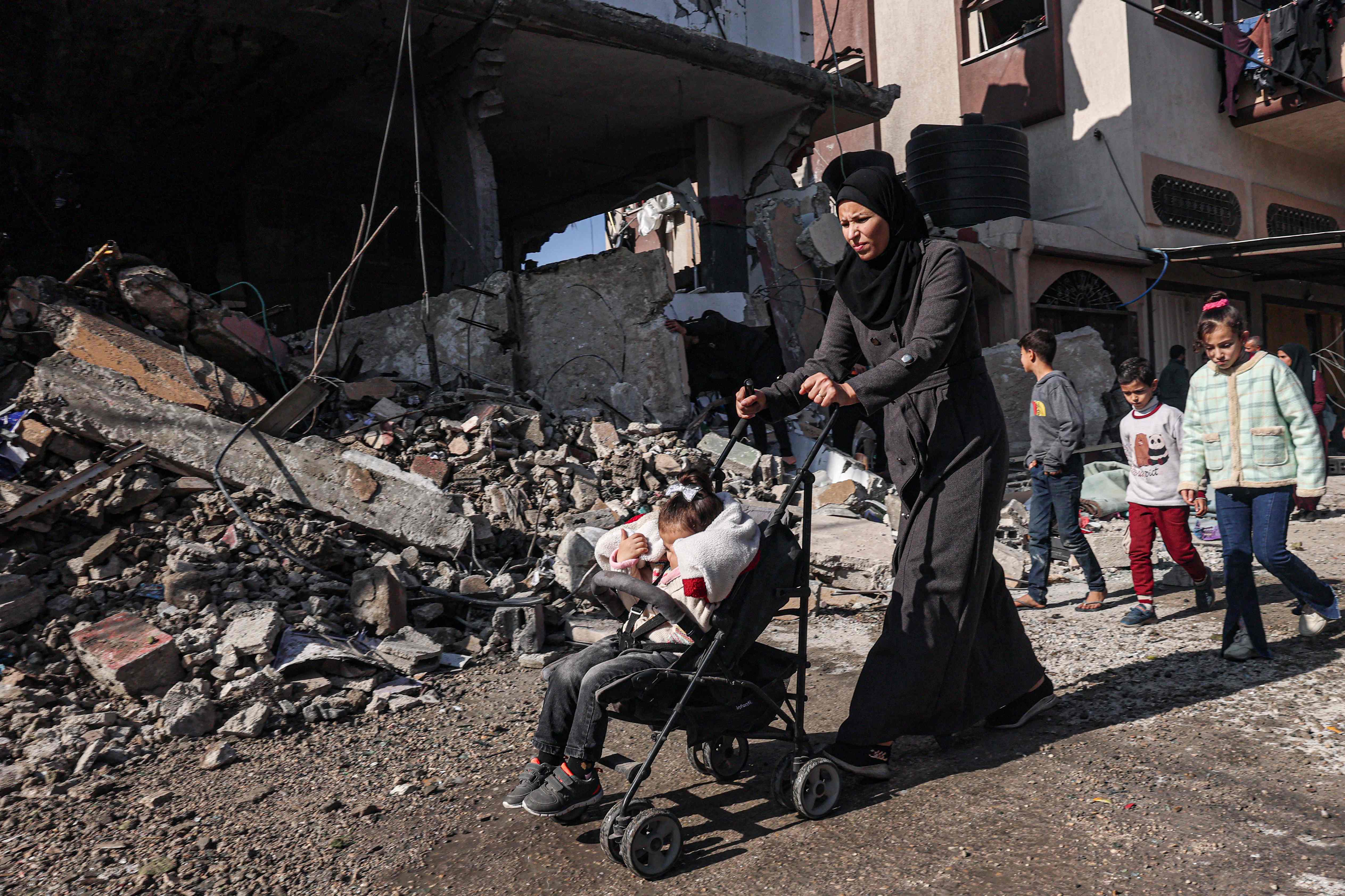 Warga berjalan melewati puing-puing bangunan setelah serangan udara Israel di kamp pengungsi Rafah di selatan Jalur Gaza.