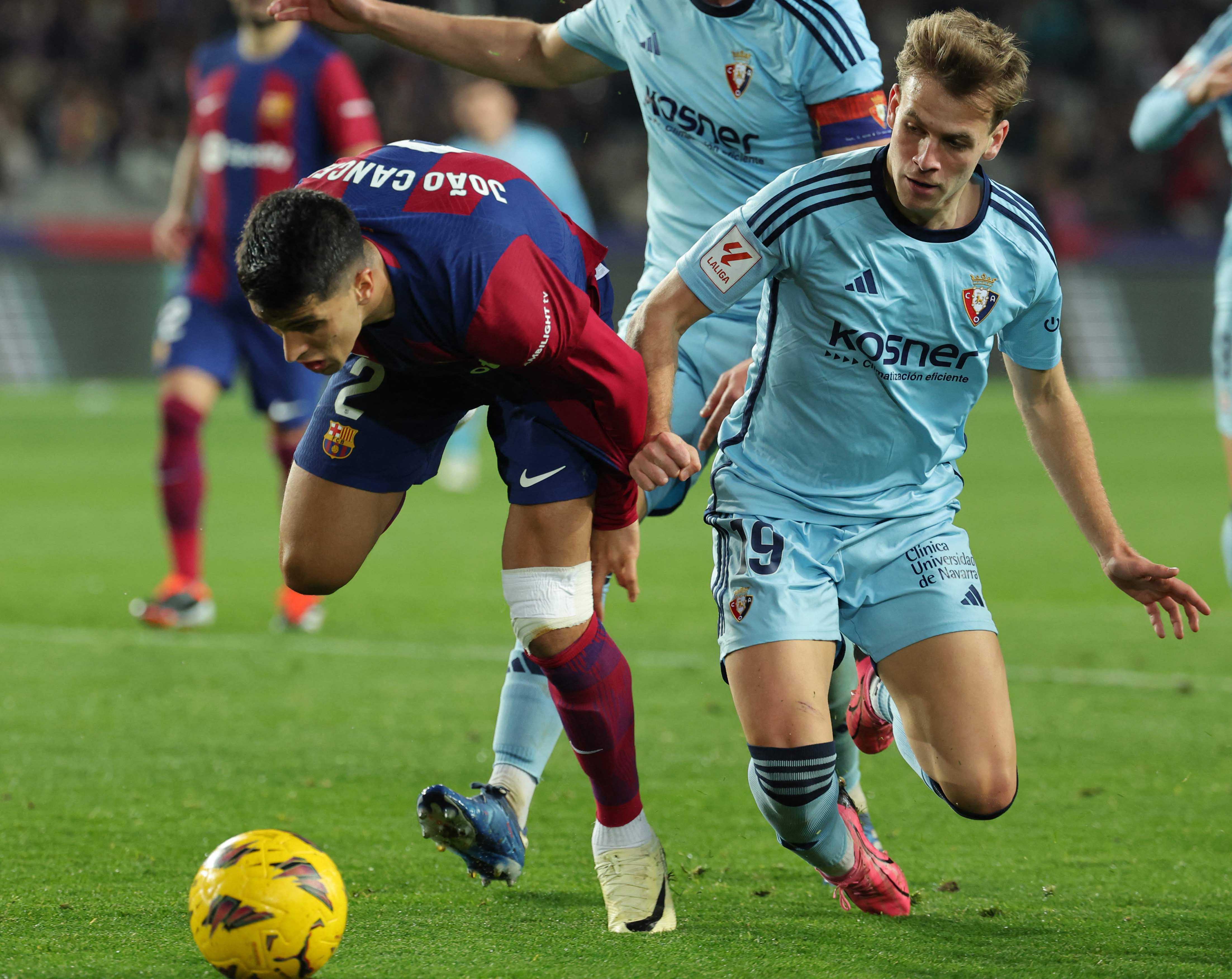 Bek Barcelona Joao Cancelo (Kiri) berebut bola dengan gelandang Osasuna Pablo Ibanez di Estadi Olimpic Lluis Companys di Barcelona, kemarin.