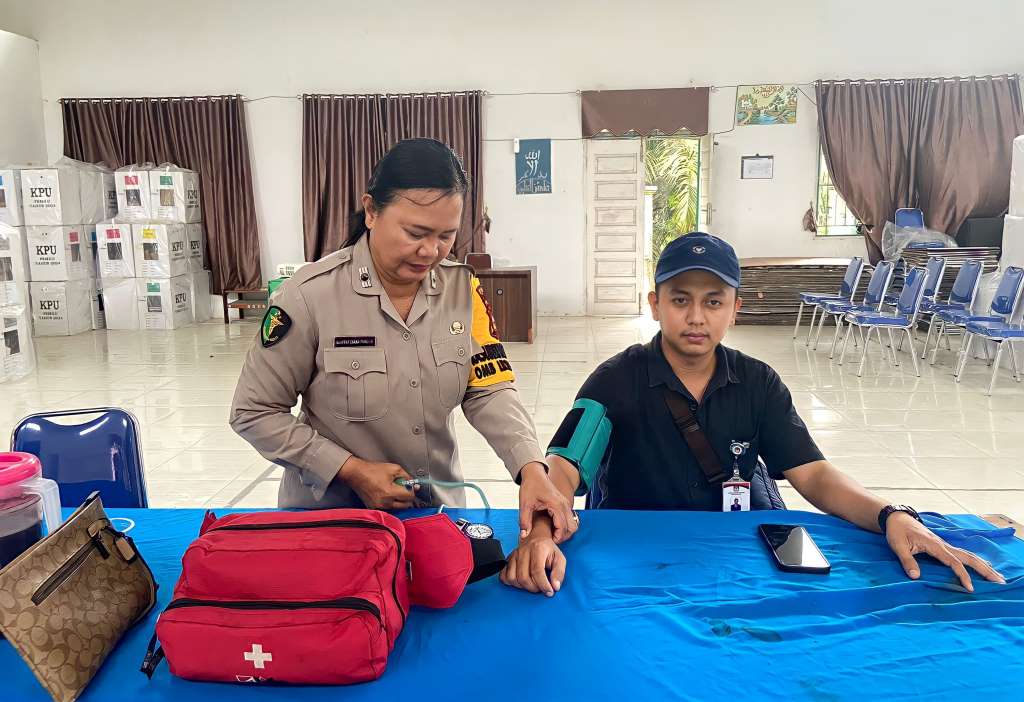 Salah satu personel Bidokkes Polres Siak melakukan pemeriksaan kesehatan kepada petugas TPS, di kantor PPK Kecamatan Dayun, Siak, Riau.