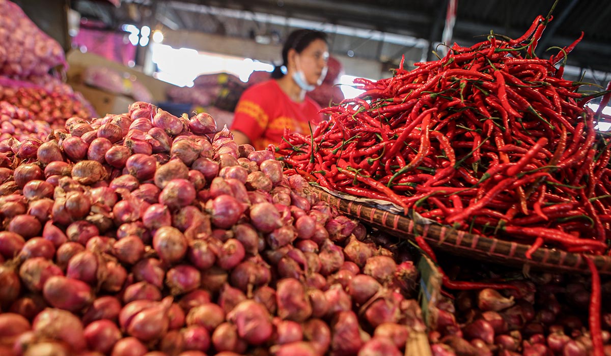 Ilustrasi.  Seorang pedagang bawang dan cabai menunggu pembeli.