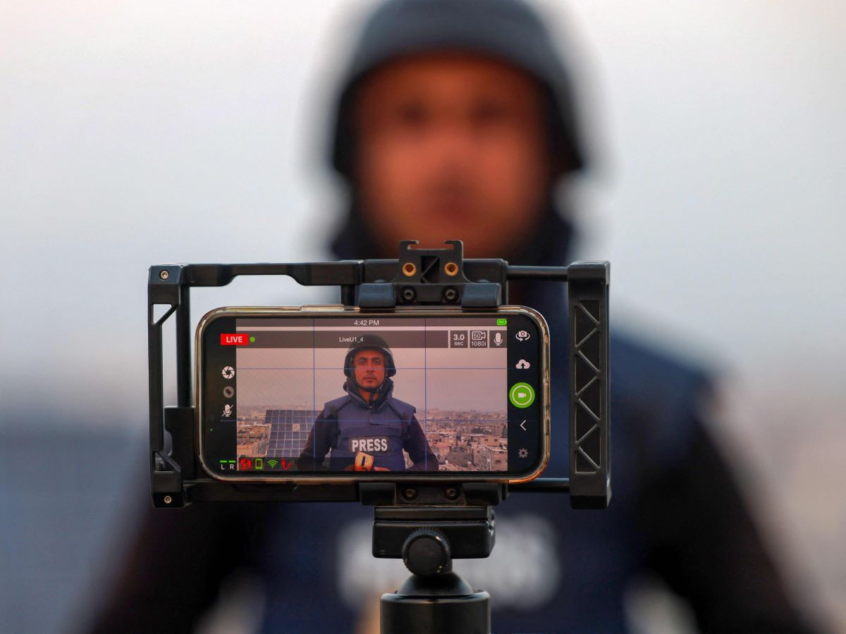 Seorang jurnalis Palestina menggunakan ponselnya untuk melakukan siaran langsung di Rafah di Jalur Gaza selatan pada 27 Desember 2023.