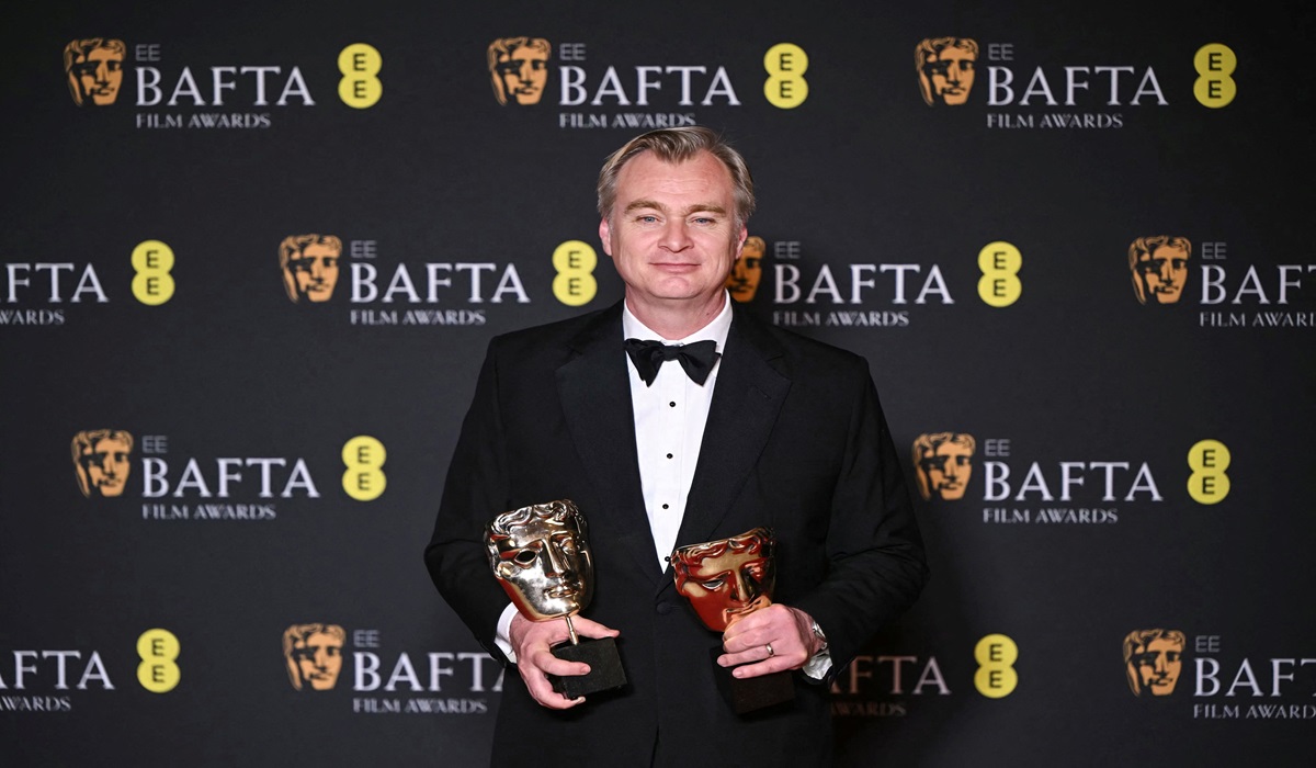 Sutradara film Oppenheimer, Christopher Nolan, berpose dengan penghargaan BAFTA untuk film terbaik dan sutradara terbaik.
