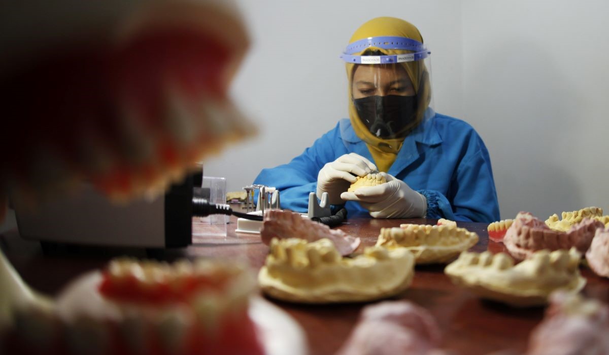 Ilustrasi: petugas menyelesaikan pesanan gigi porcelaine atau gigi palsu