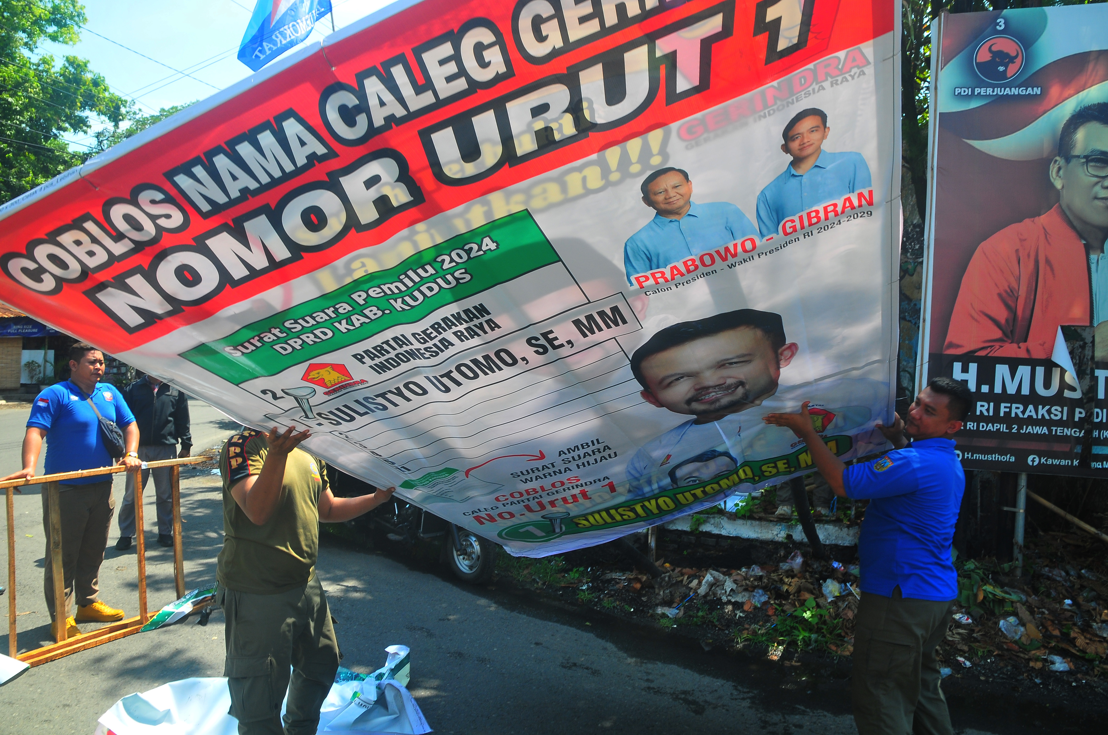 Sejumlah anggota Satpol PP melepas baliho alat peraga kampanye (APK) yang melanggar aturan di Kudus, Jawa Tengah, Rabu (27/12/2023)