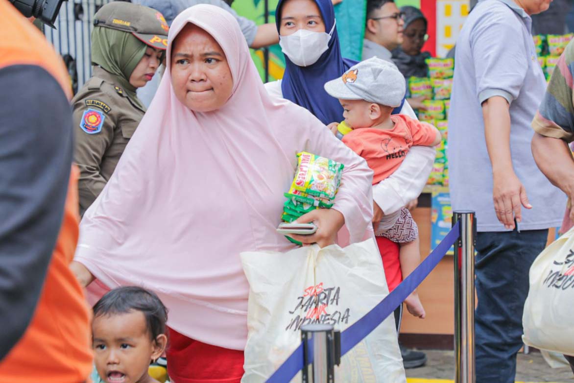 Masyarakat membawa kebutuhan pokok dari program Sembako Murah yang diadakan oleh Pemprov DKI Jakarta.