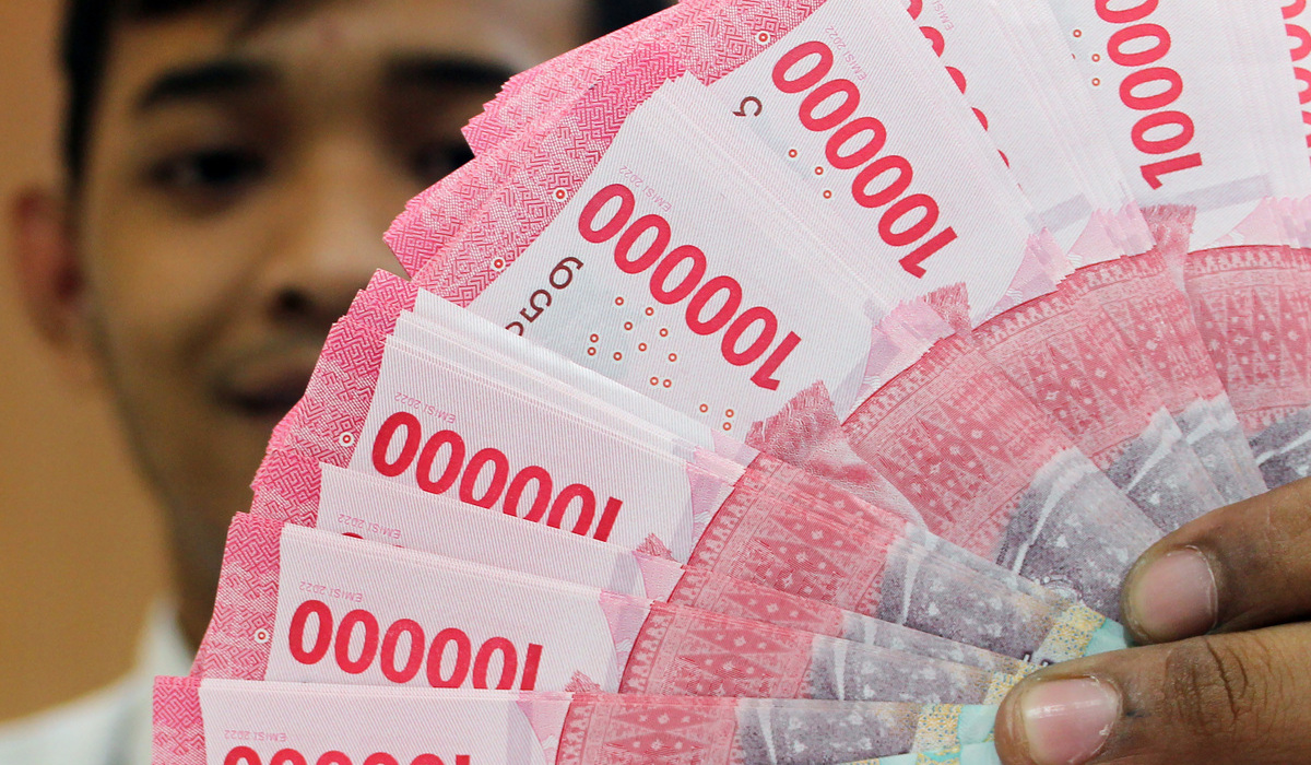 Petugas bank menunjukkan lembaran uang rupiah di salah satu bank di Jakarta.