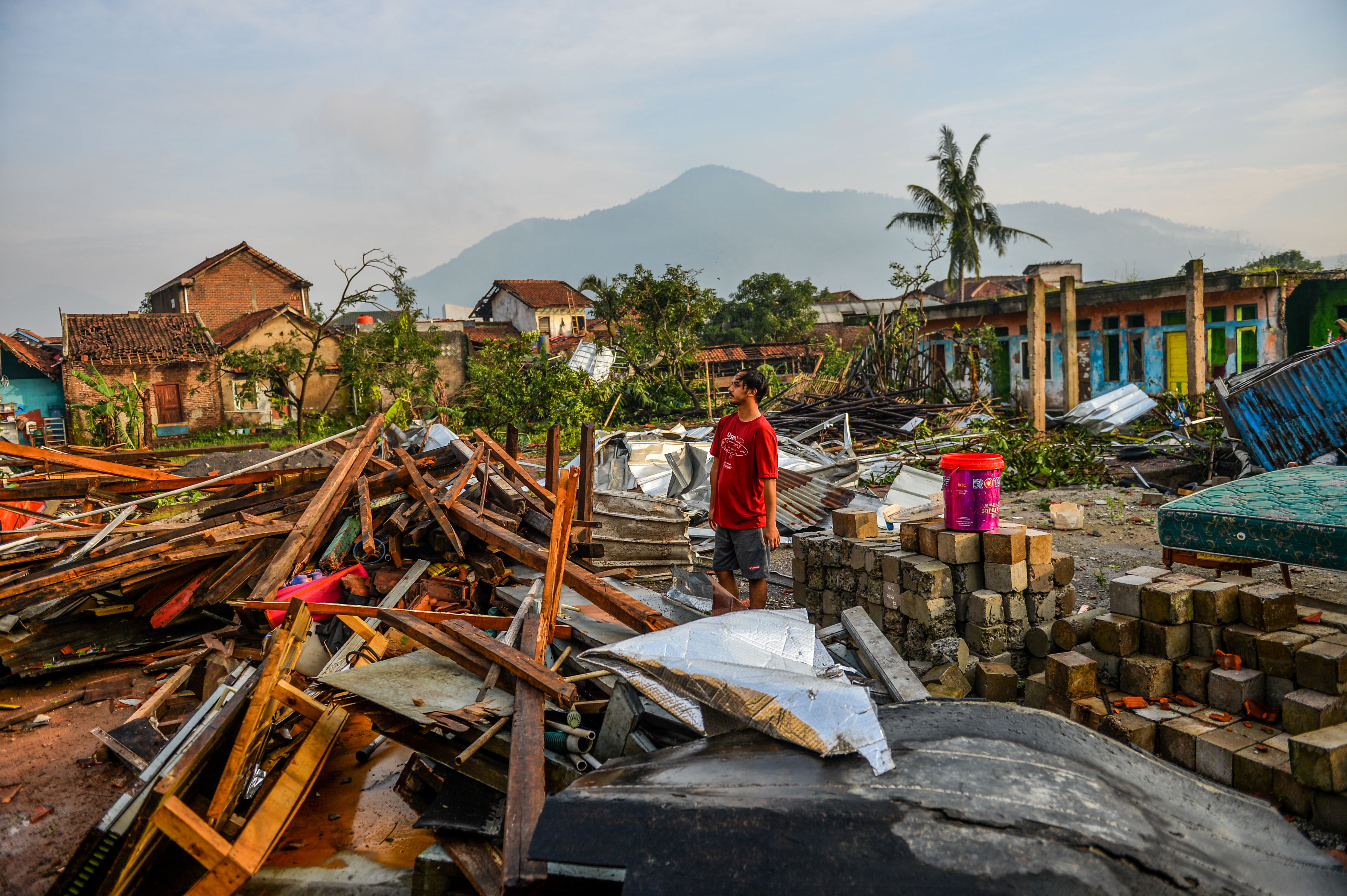 Warga berdiri di antara puing rumah yang hancur akibat angin puting beliung di Desa Sukadana, Kabupaten Sumedang, Kamis (22/2).