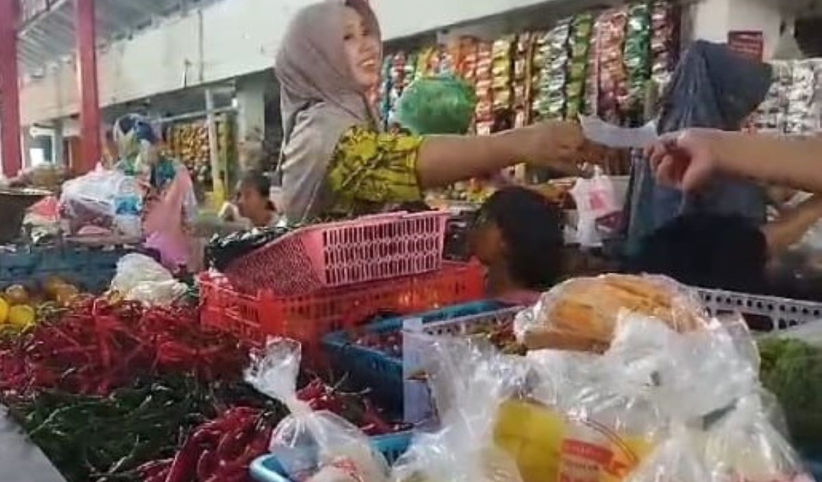 Pedagang sayur mayur di Pasar Martoloyo Kota Tegal, Vinita, menerima pembayaran dari konsumen.