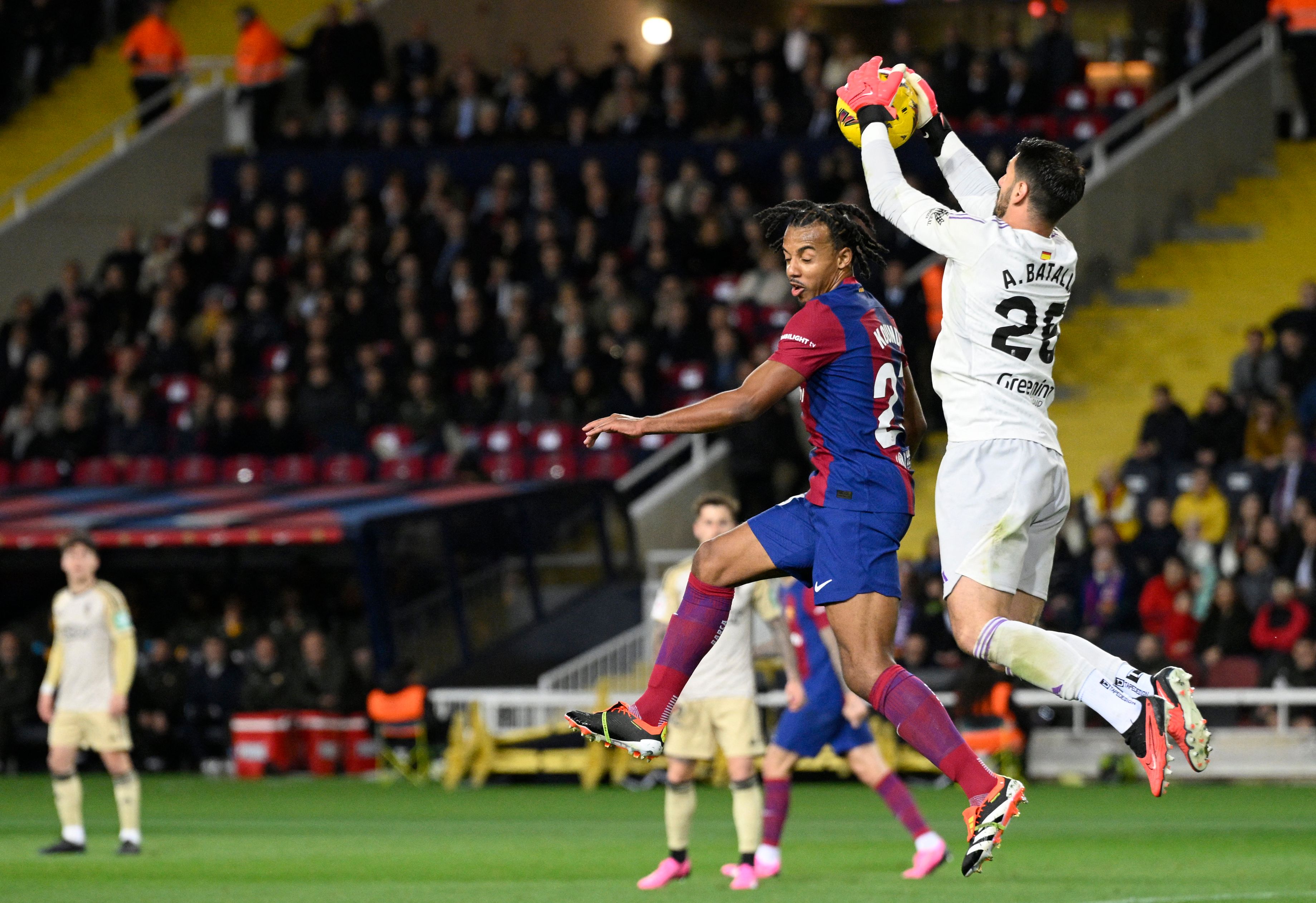 Penjaga gawang Granada #25 Augusto Batalla melompat untuk melakukan penyelamatan di samping bek Barcelona #23 Jules Kounde.