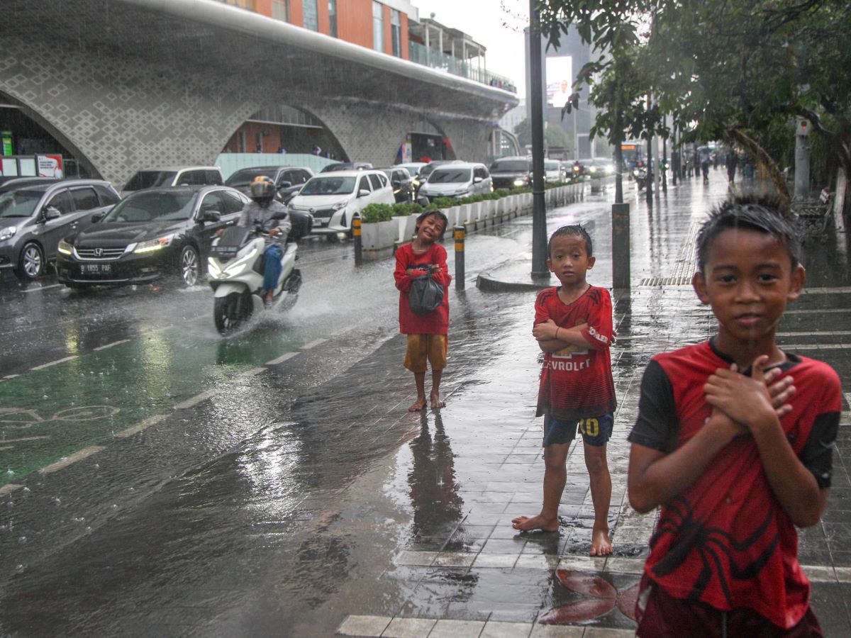 Anak-anak berpose seusai bermain hujan di Jalan Thamrin, Jakarta, Kamis (11/01/2024).