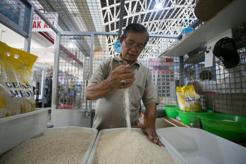 Pedagang menata beras di pasar.