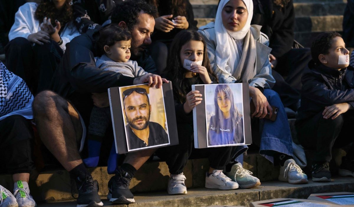 Demonstran mengangkat potret jurnalis Reuters Issam Abdallah (kiri) dan reporter Al-Mayadeen asal Libanon, Farah Omar, yang terbunuh.