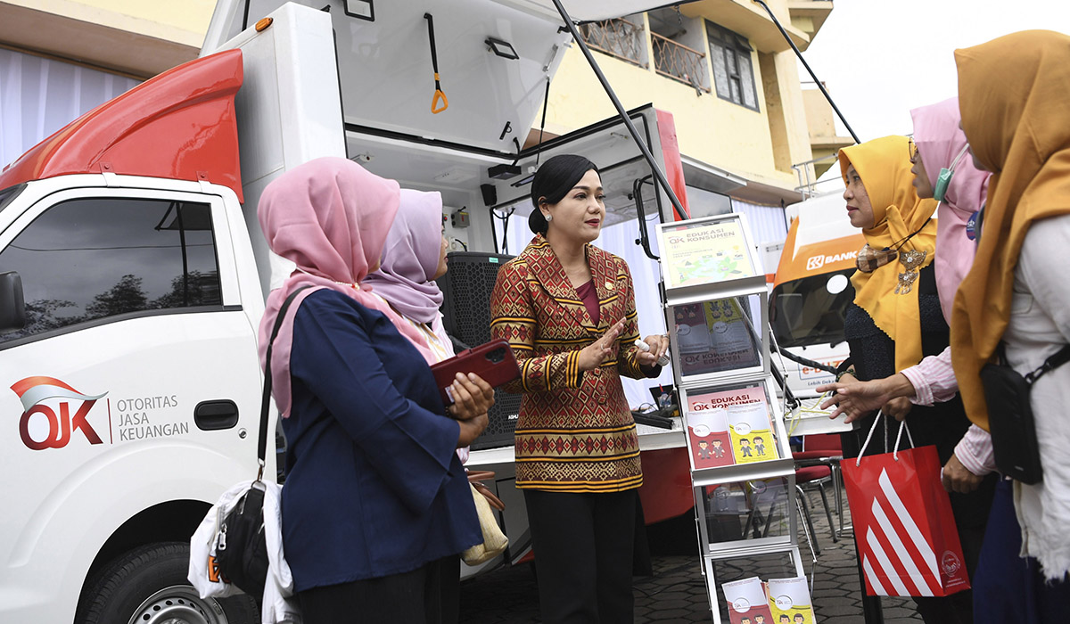 Perwakilan OJK berbincang dengan warga di samping Mobil SiMolek usai memberikan materi edukasi keuangan.