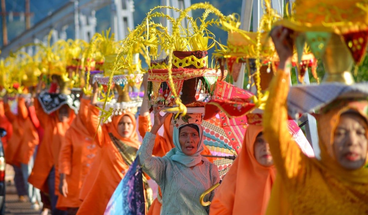 Sejumlah ibu-ibu menjunjung dulang di kepala mereka yang berisi air perasan limau, saat acara tradisi Limau Barongge, di Sungai Pisang 