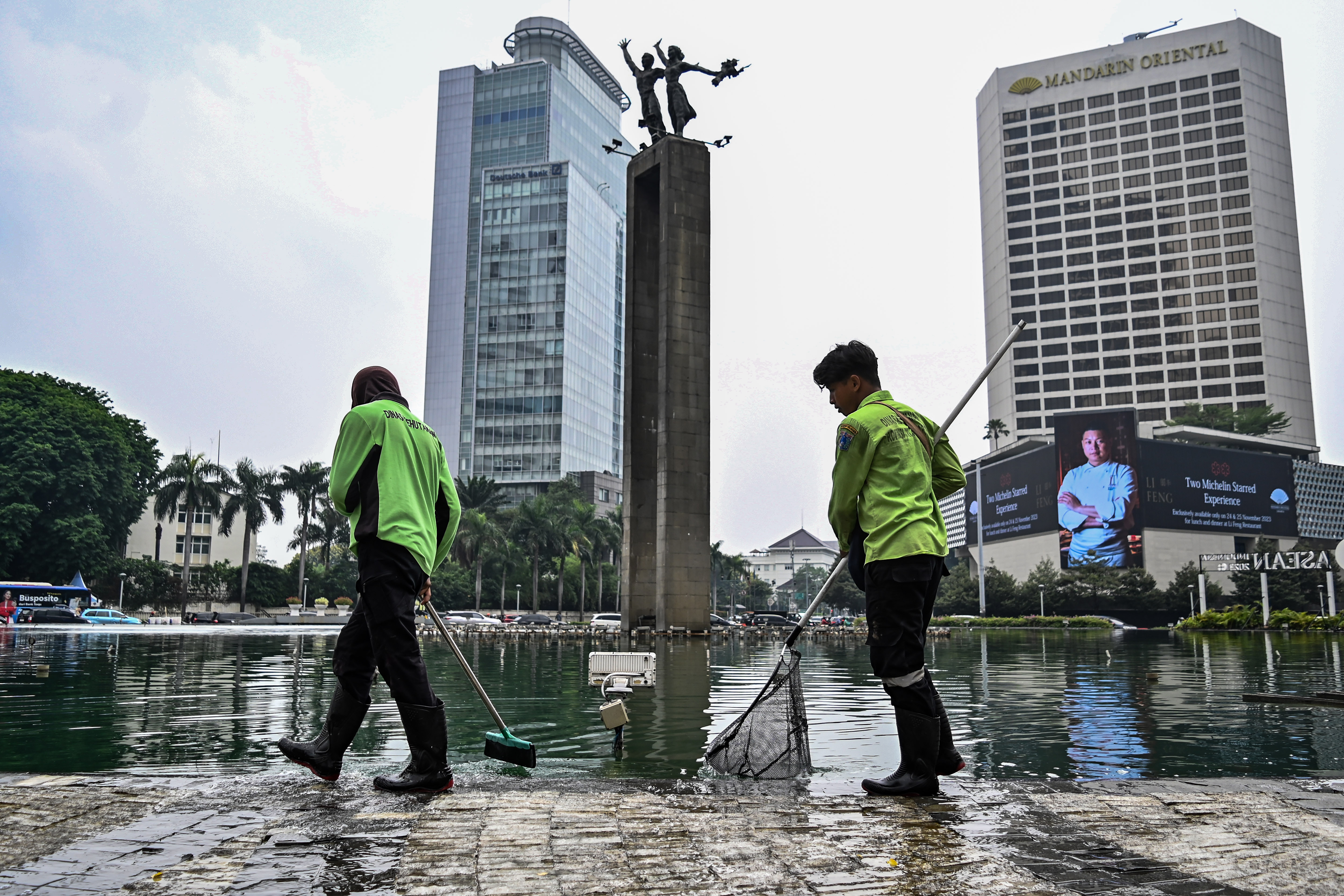 Petugas Dinas Pertamanan dan Hutan Kota Provinsi DKI Jakarta membersihkan busa di kolam air mancur Bundaran HI, Jakarta