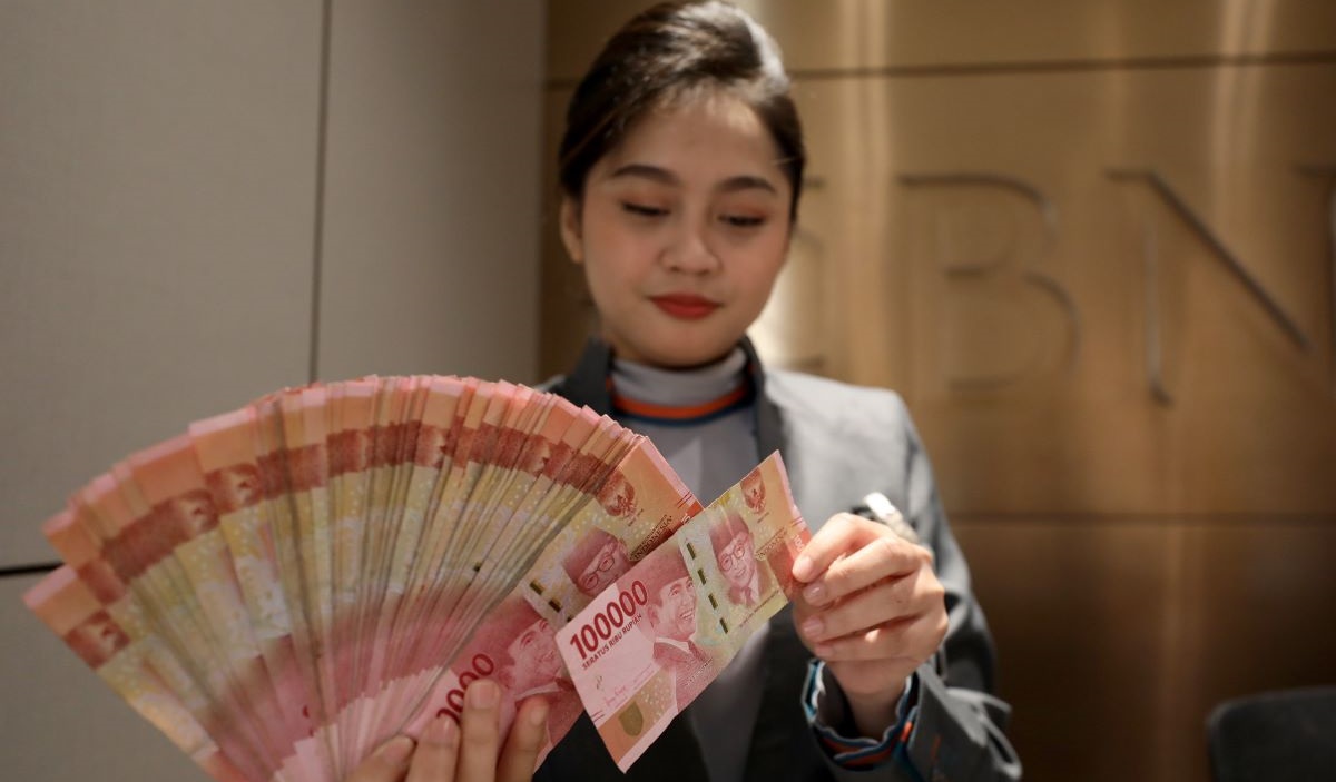 Petugas menunjukkan mata uang rupiah di salah satu kantor cabang PT Bank Negara Indonesia (BNI) Tbk. di Jakarta, Jumat (23/2/2024).