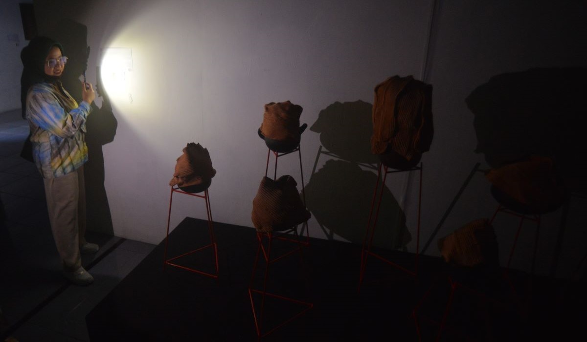 Pengunjung melihat karya seni rupa menggunakan senter, akibat pemadaman listrik.