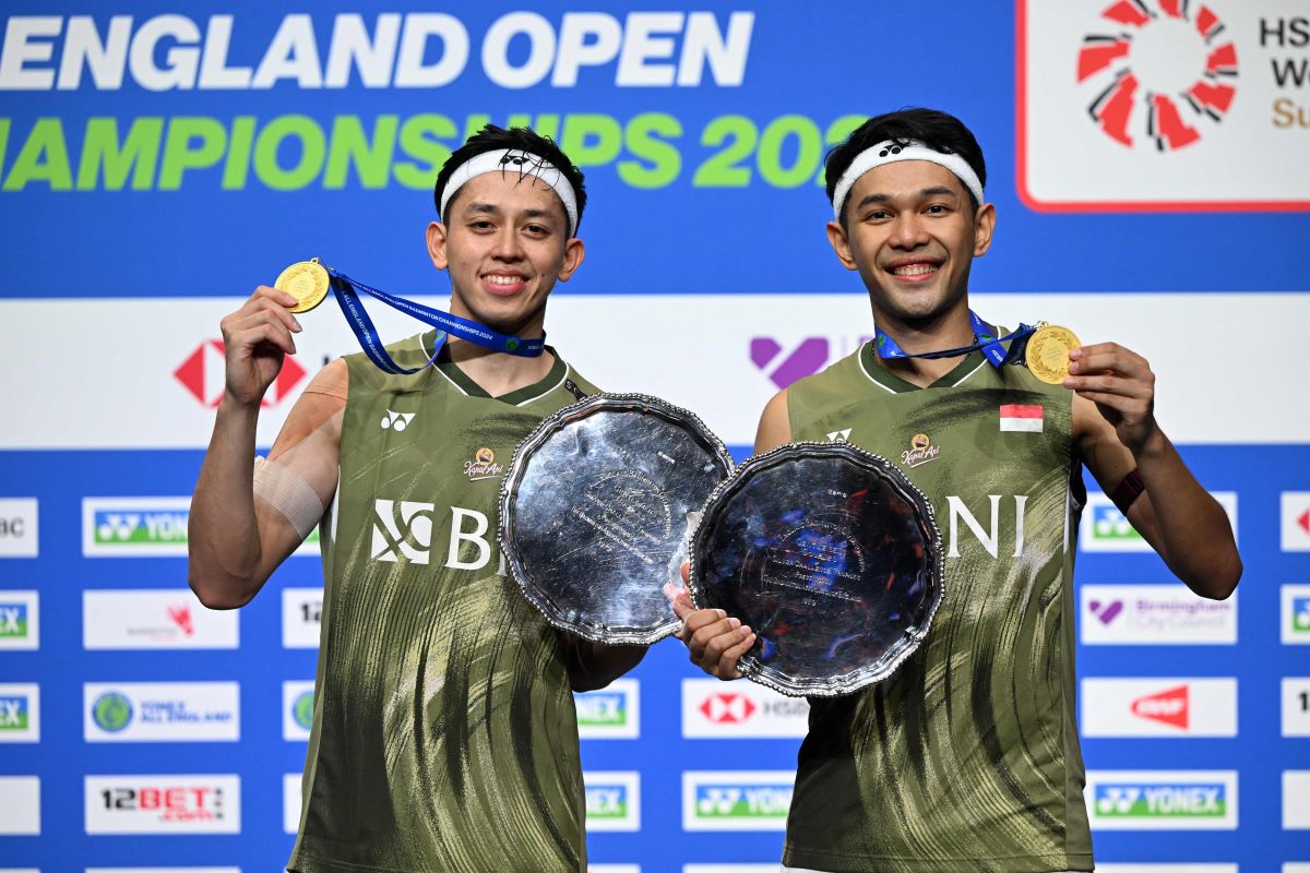 Fajar Alfian dan Muhammad Rian Ardianto memamerkan trofi juara All England 2024.