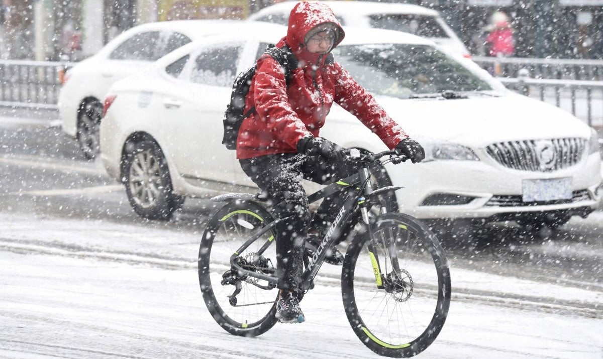 Seorang pemuda mengendarai sepeda saat hujan salju lebat di Huai'an, di provinsi Jiangsu, Tiongkok timur pada 4 Februari 2024.