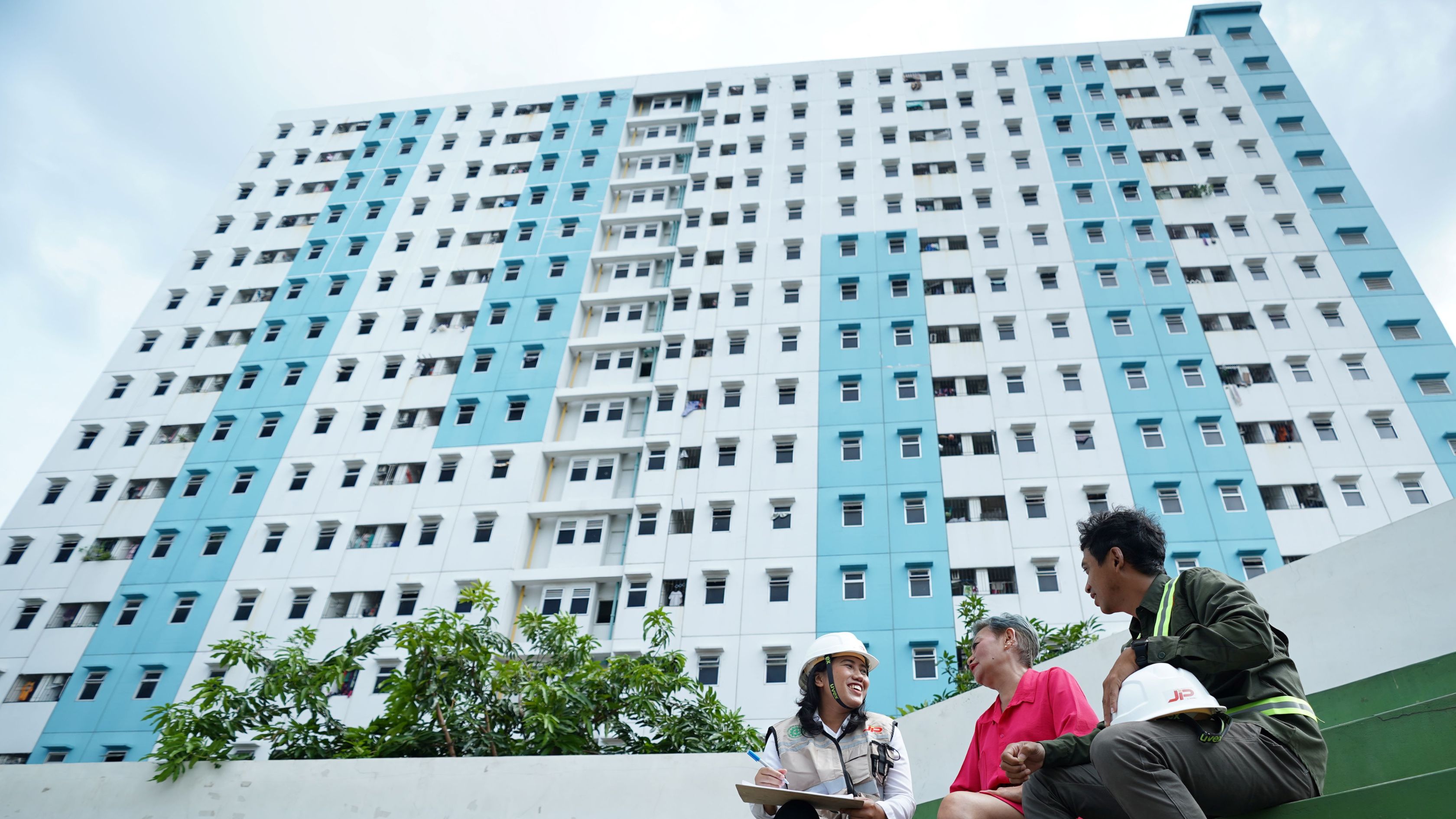 Petugas JIP berbincang dengan latar rusunawa.