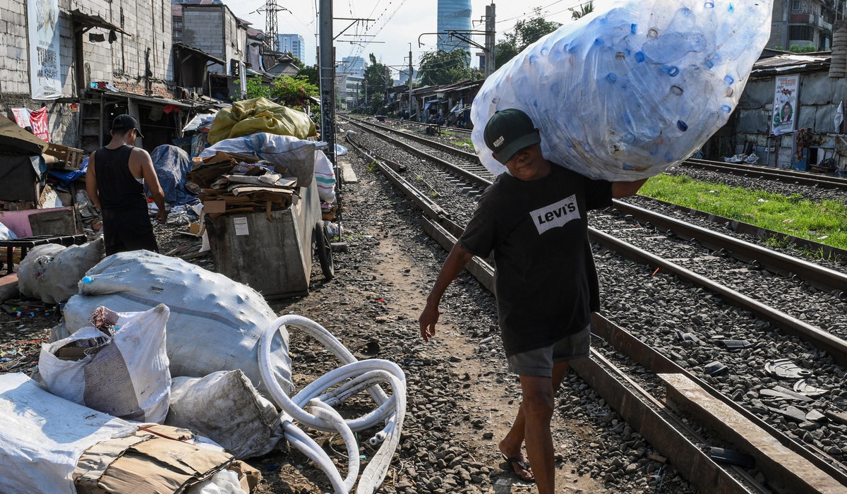 Pemulung memikul botol plastik di area perlintasan kereta api Palmerah-Tanah Abang, Jakarta.