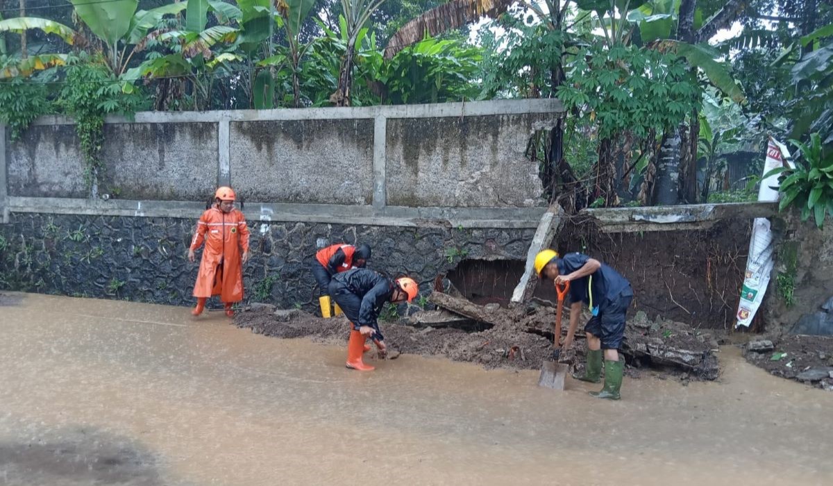 Personel BPBD Kota Sukabumi dibantu petugas pemadam kebakaran menangani dampak banjir limpasan