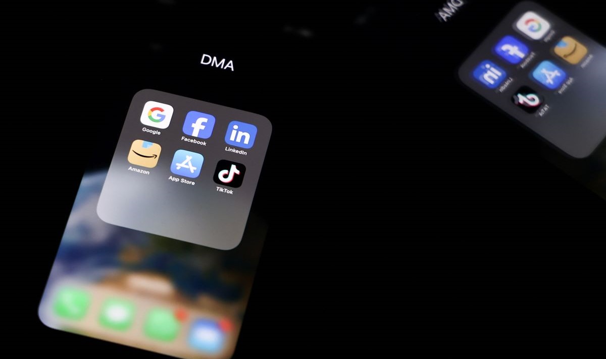 Refleksi logo platform online Google, Facebook, Linkin, Amazon, Apple Store, dan Tiktok di layar ponsel pintar.