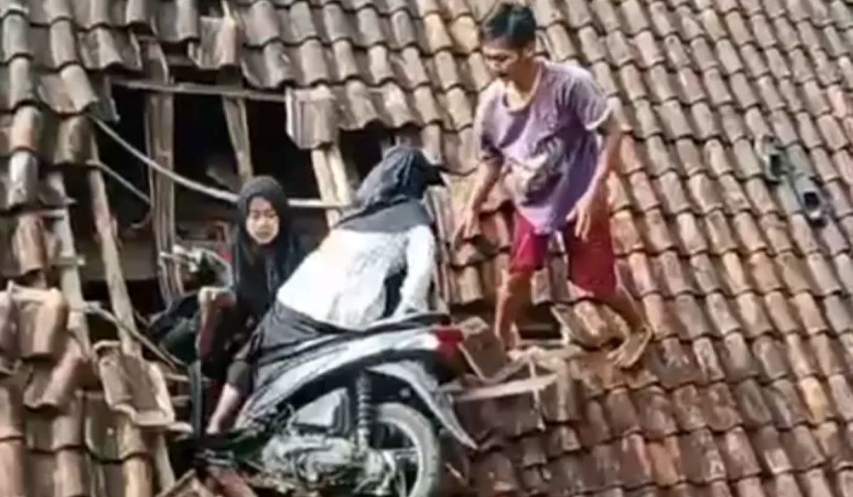 Dua pemotor menyangkut di atap rumah