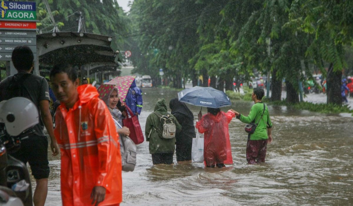 Petugas membantu mengatur lalu lintas saat banjir menggenangi Jalan Suprapto, Cempaka Putih, Jakarta Pusat 