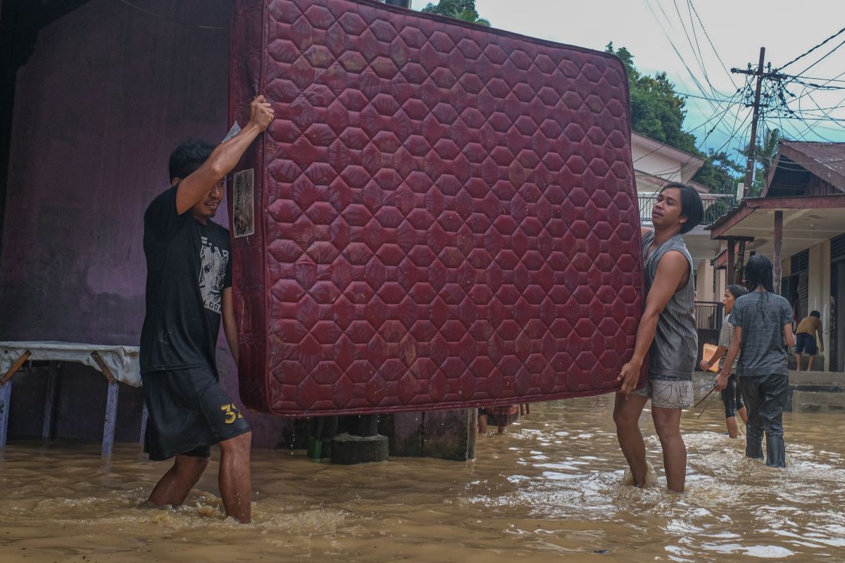 Warga menyelamatkan barang-barang dari banjir.