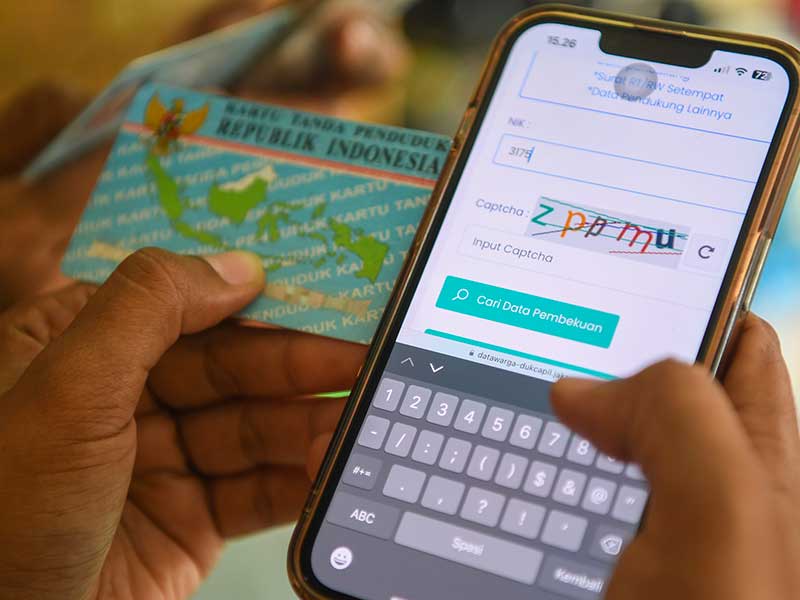 Warga mengecek nomor induk kependudukan (NIK) melalui laman datawarga-dukcapil.jakarta.go.id dengan ponselnya di Jakarta. 