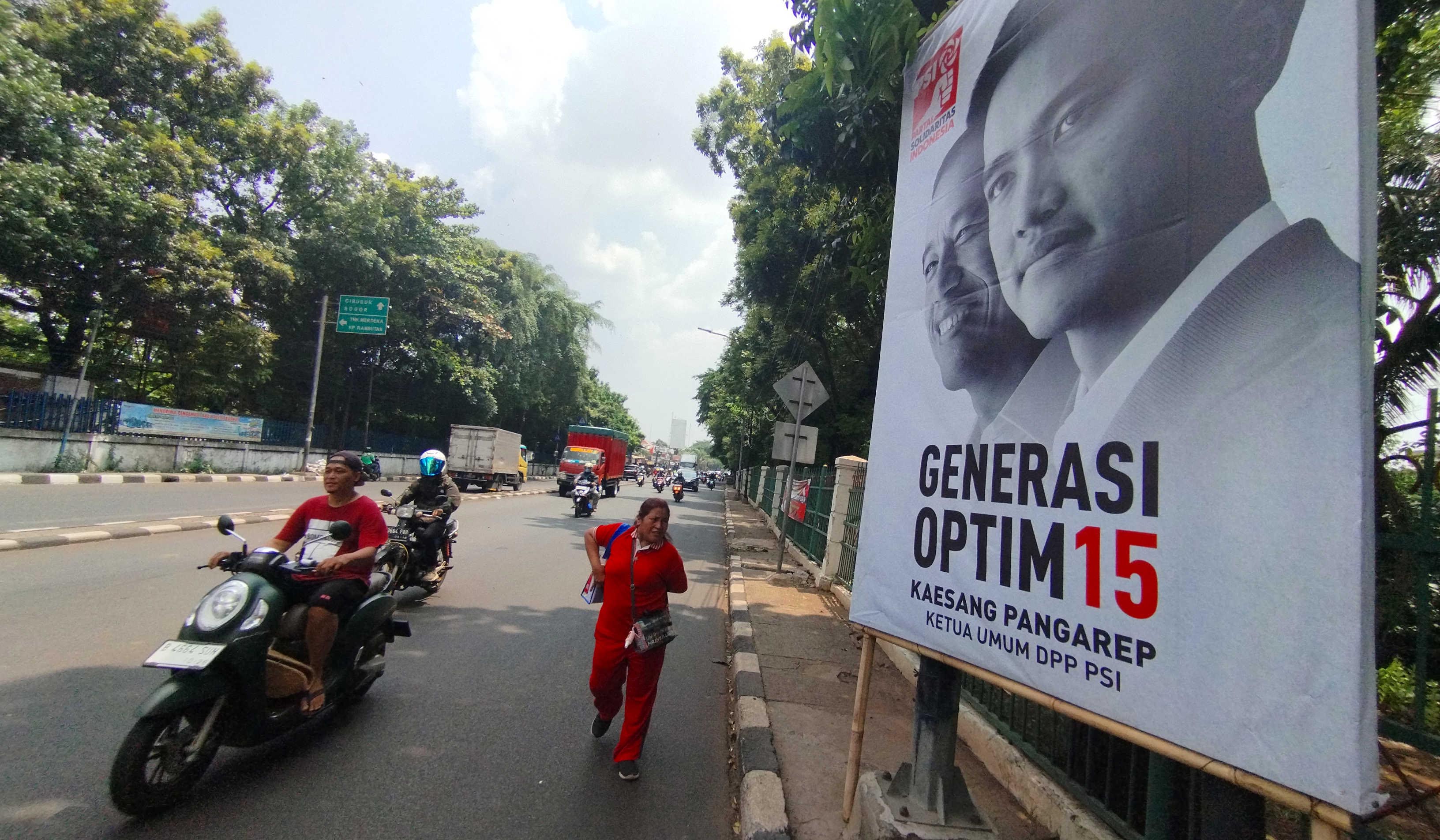 Warga melewati baliho bergambar Kaesang Pangarep yang merupakan Ketua Umum PSI.